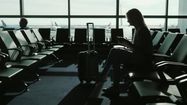 Una donna d'affari gode di un tablet nel terminal di un aeroporto internazionale. Aspettando il mio volo — Video Stock