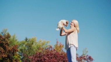 Bir kadın onun elinde bir köpek yavrusu ile gökyüzüne yüksek atlama.