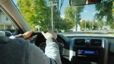 Direksiyondaki bir adamın elleri tipik bir Amerikan banliyösüne gider.