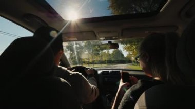 Genç çok ırklı çift sürüş bir adam araba, seyahat, bir kadın bir smartphone yakın kullanır.