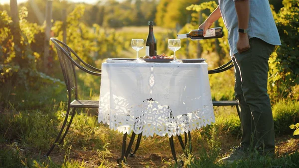 Чоловік вливає вино в келих, готується до романтичної вечері на природі — стокове фото