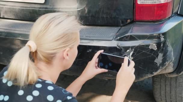 Uma mulher fotografa um pára-choques de carro danificado — Vídeo de Stock