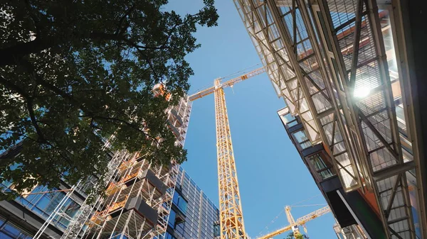 Guindaste torre no distrito de negócios da cidade moderna. Nas janelas dos edifícios de escritórios o sol é refletido. Baixo ângulo tiro largo — Fotografia de Stock