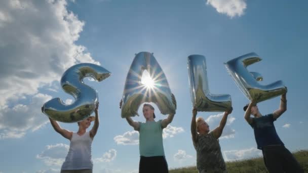 Um grupo de pessoas segurando balões na forma de letras - VENDA — Vídeo de Stock