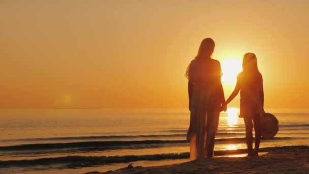 Mamá e hija de siete años juntas miran la hermosa puesta de sol sobre el mar. Vacaciones con un concepto de niño — Vídeo de stock