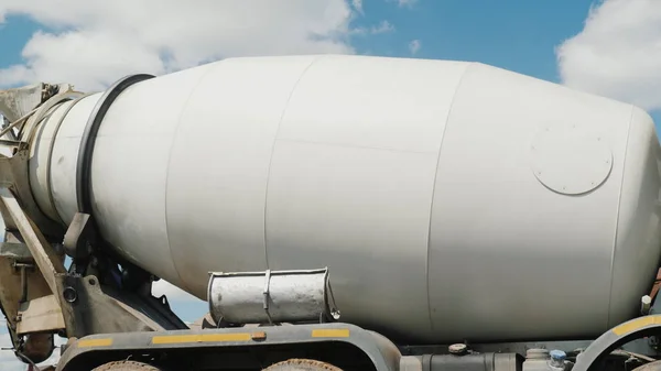 A large industrial concrete mixer, a tank with an ieton rotates against the sky. Concrete delivery and building materials concept