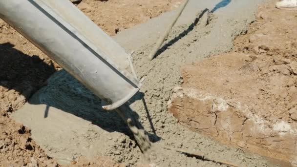 Fertigbeton fließt durch das Rohr in das Fundament. Arbeitsvibrator verdichtet es — Stockvideo