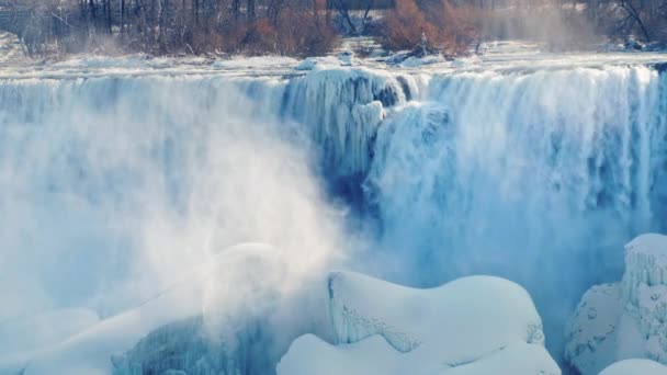 Saison d'hiver aux chutes Niagara. Les rayons du soleil illuminent le brouillard et les éclaboussures de la cascade 
