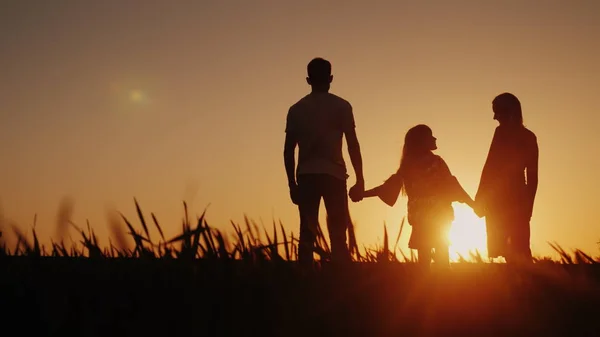 Une famille heureuse de trois personnes rencontre l'aube dans un endroit pittoresque. Tenant la main — Photo