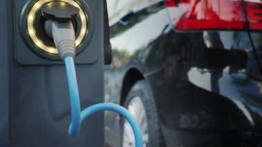 Bir elektrikli araba şehir sokak, bir close-up bir araba için bağlı bir kablo üzerinde şarj