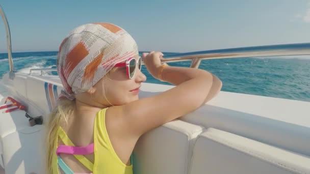 La chica del pañuelo navega en un barco. Mira paisajes por la borda. Vacaciones de verano con un niño — Vídeos de Stock