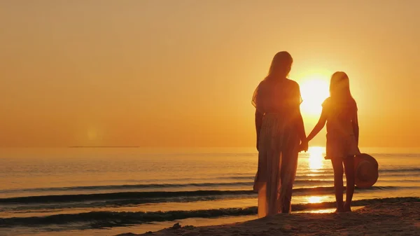 Máma a dcera sedmi let společně podívat na krásný západ slunce nad mořem. Dovolená s konceptem dítě — Stock fotografie