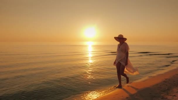 Γυναίκα τουριστικές βόλτες ευτυχώς στην άκρη τα ύδατα, κοντά στη θάλασσα στο ηλιοβασίλεμα — Αρχείο Βίντεο
