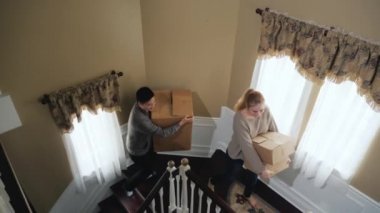 Çok ırklı bir çift merdivenlerden tırmanıyor, ellerindeki karton kutular taşır. Yeni bir ev ya da yeni eve taşınma partisi kavram için hareket. Slow motion video