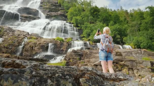 Womanfotografiert den höchsten Wasserfall Norwegens. Der Legende nach hat das Wasser dieses Wasserfalls eine verjüngende Wirkung — Stockvideo