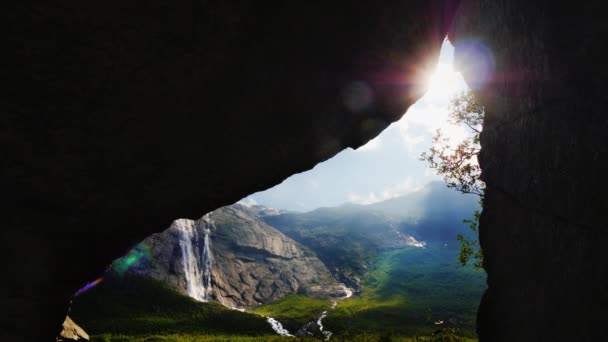 太陽が岩のアーチを通して輝き、高い山々に囲まれた絵のような谷を見ることができます。ノルウェーの素晴らしい自然、観光客の夢 — ストック動画