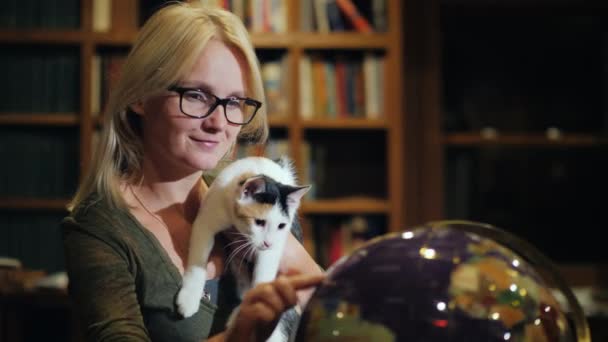 Donna con un gatto in mano guarda il globo — Video Stock