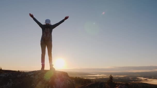 Crane shot of A successful woman traveler at the top of the mountain raises her hands up. Reach the top of the concept. — Stock Video