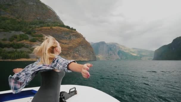 Una mujer está de pie en la proa del barco que navega sobre el fiordo en Noruega. Cámara lenta de vídeo de alta definición — Vídeos de Stock