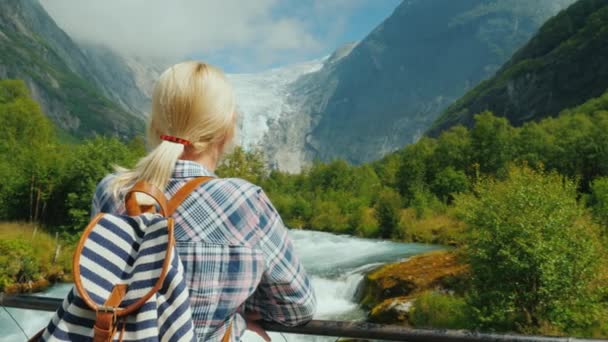 Женщина-путешественница смотрит на красивые горы и ледник на вершине. Ледник Бриксдаль в Норвегии — стоковое видео
