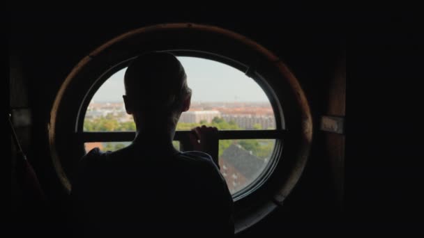 Silueta Una Mujer Mirando Por Una Ventana Redonda Los Tejados — Vídeo de stock