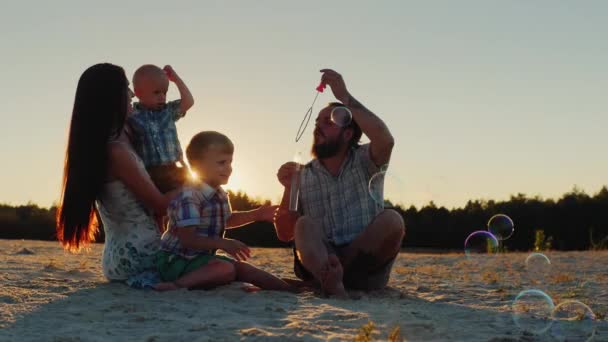 Giovani genitori e due figli della famiglia che giocano con le bolle di sapone — Video Stock