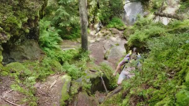 Vista dall'alto: Un uomo aiuta una donna a salire un sentiero ripido. Trekking nel bosco — Video Stock