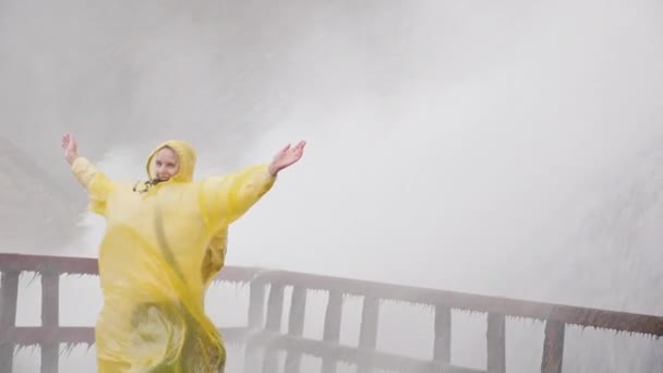 La mujer está satisfecha con las salpicaduras de agua bajo las Cataratas del Niágara. Viaje a la cueva de los vientos. Vídeo en cámara lenta — Vídeos de Stock