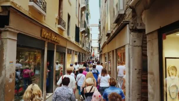 ヴェネツィア、イタリア、2017 年 6 月: 観光客は土産物店近くヴェネツィア通りに沿って歩いているし、ブランドを取り扱うブティック。彼らは明るい窓に沿って進みます。イタリアの観光やショッピング — ストック動画
