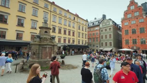 Sztokholm, Szwecja, lipca 2018: Rynek Starego Miasta w centrum Gamla Stan. Turystów spacer wokół piękna fontanna — Wideo stockowe