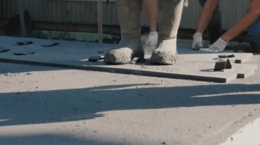 Bir grup inşaatçılar bir paspas ile taze beton işaretleyin. Terasta bir sert kaplama yapmak