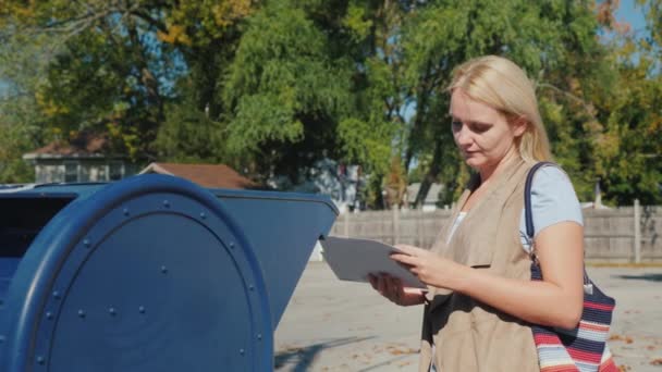 Una donna guarda le buste con delle lettere, poi le getta nella cassetta della posta blu per strada. — Video Stock