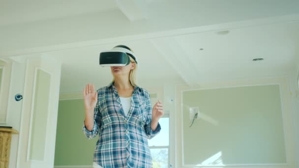 A woman in a virtual reality helmet is looking at an interior project. Augmented Reality in Construction — Stock Video