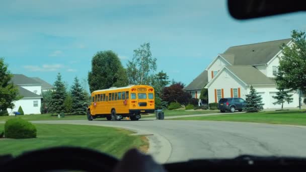 Widok z okna samochodu, który idzie po szkole żółty autobus szkolny w Stanach Zjednoczonych Przedmieście — Wideo stockowe