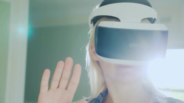 Retrato de uma mulher em um capacete de realidade virtual. O sol com destaques brilha da janela atrás dela . — Vídeo de Stock