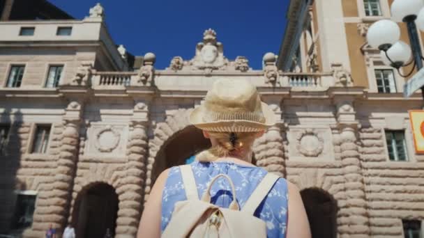 Una turista con bandera sueca va al arco cerca del parlamento. Uno de los lugares más populares y reconocibles de la ciudad — Vídeo de stock