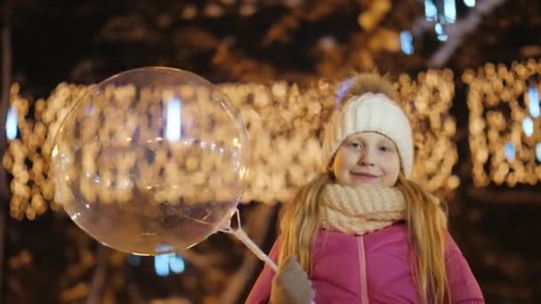 Πορτρέτο του ένα κορίτσι σε ζεστά ρούχα με ένα μπαλόνι με μια γιρλάντα. Φόντο θολή φώτα του δρόμου — Αρχείο Βίντεο