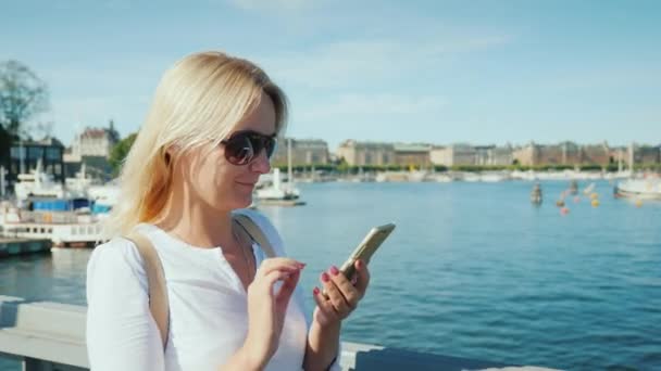 Femme avec un smartphone marchant le long du remblai de Stockholm — Video