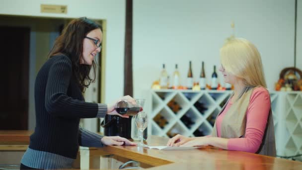 Продавец вина наливает вино в бокал для посетителя. Дегустация вин в частных винодельнях, семейном бизнесе — стоковое видео