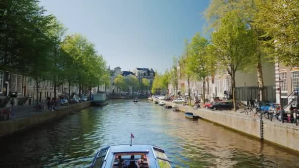 Amesterdam, Nederland, mei 2018: Boot met toeristen zeilen op het pittoreske kanaal in Amsterdam — Stockvideo