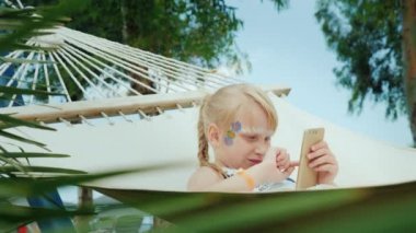 Aqua-korkunç küçük bir kızla yüzünde yatıyor bir hamak cep telefonu üzerinde oynarken havuz kenarında üzerinde