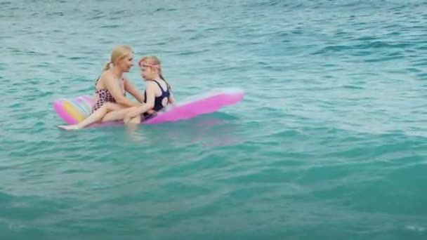 Активний сімейний відпочинок з дітьми, молода жінка з дочкою весело їздити на хвилях на надувному матраці — стокове відео