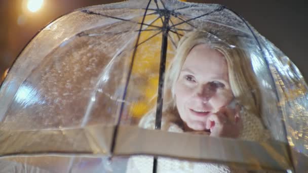 Kobieta w średnim wieku pod parasolami rozmawia przez telefon. Śnieg — Wideo stockowe