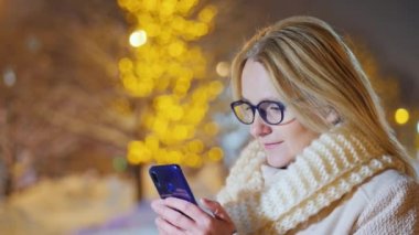 Bir smartphone kullanarak sokakta akşamları sıcak giysiler içinde bir kadın