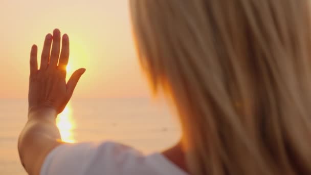 女性は、海の上に昇る太陽に彼女の手を拡張します。暖かさおよび概念のフライをお楽しみください。 — ストック動画