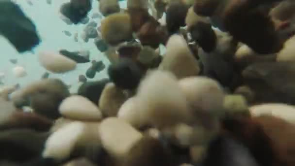 海サーフは、異なる方向に小石を発生させます。ビデオは水の下で撮影されました。 — ストック動画