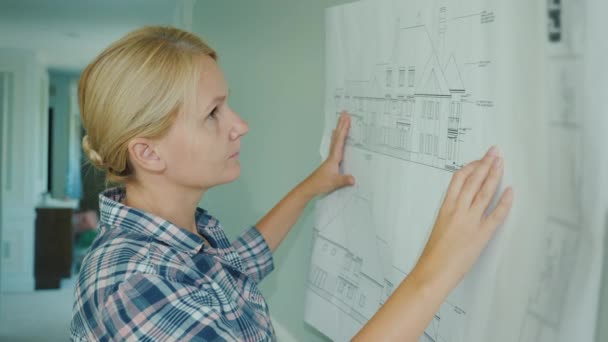 Νεαρή γυναίκα σχεδιαστής κοιτάζει σχέδιο στο σπίτι — Αρχείο Βίντεο