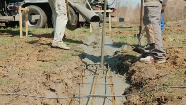 Workers with a hand-held vibrator and shovel work on pouring the foundation — Wideo stockowe