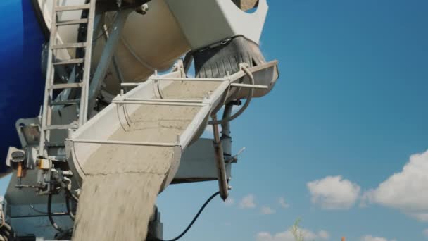 Levering van fabriek afgewerkt beton. Beton stroomt door een goot van een mixer tegen een blauwe hemel op een duidelijke zomerdag — Stockvideo