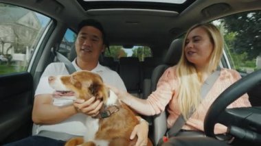 Genç bir beyaz kız araba kullanıyor ve Asya sevgilisi ile bir köpek ile onun kollarında iletişim kurar